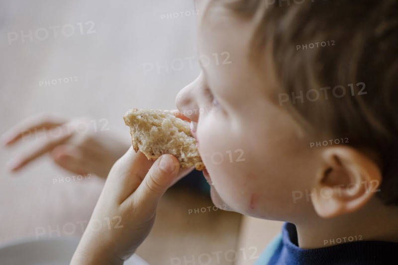 Symbolic photo on the topic of nutrition in children. A boy holds a roll or bread in his hand. Berlin