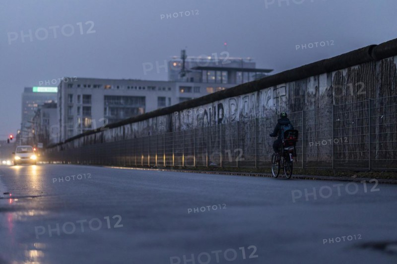 A cyclist stands out in front of the Berlin Wall in Berlin
