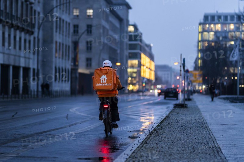 An employee of the delivery service Lieferando drives along Wilhemstrasse in the evening in Berlin