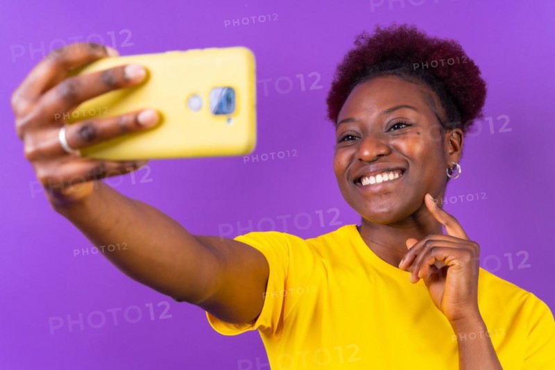 Young african american woman isolated on a purple background smiling and making a selfie