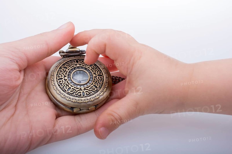 Retro style pocket watch in hand on white background