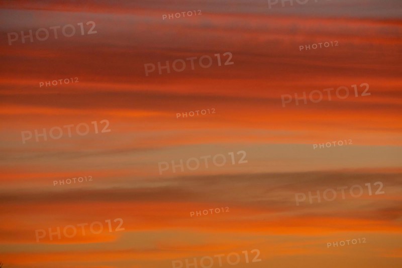 Evening reddish orange cloud structures against blue sky