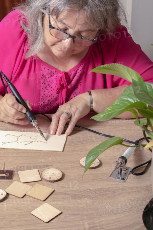 Front view of a woman burning a wooden board with a pyrographer