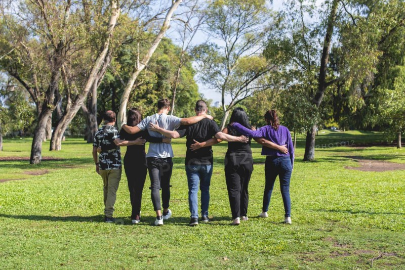 Rear view of a group of friends hugging while walking. Friendship and support concept