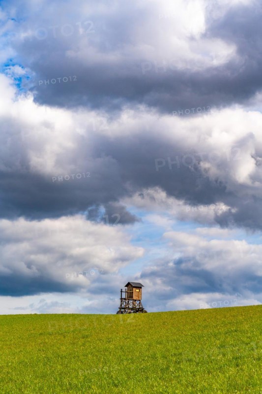 Mobile raised hide in an empty field under dramatic clouds