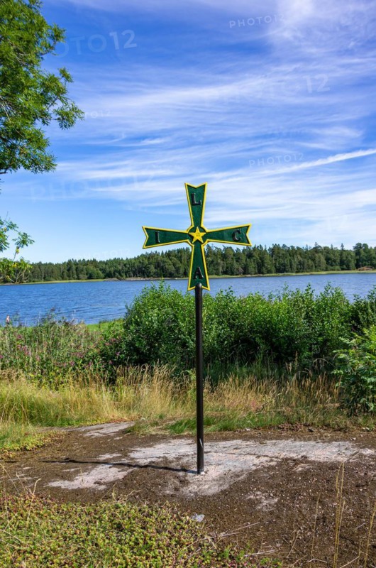 Old historical iron cross of paws with Masonic symbolism in a grove in front of Laeckoe Castle by Lake Vaenern
