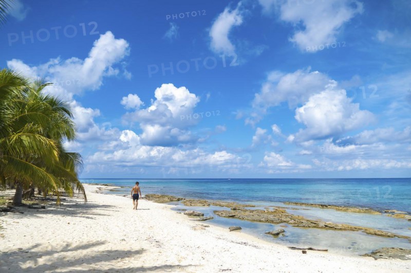 Athletic young man walking on a paradise beach. Concept Vacation