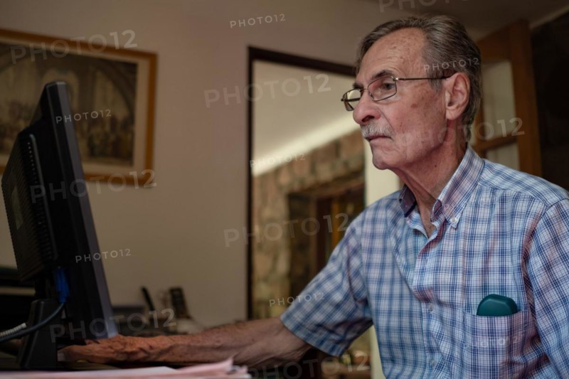 Older man very concentrated in front of computer at home