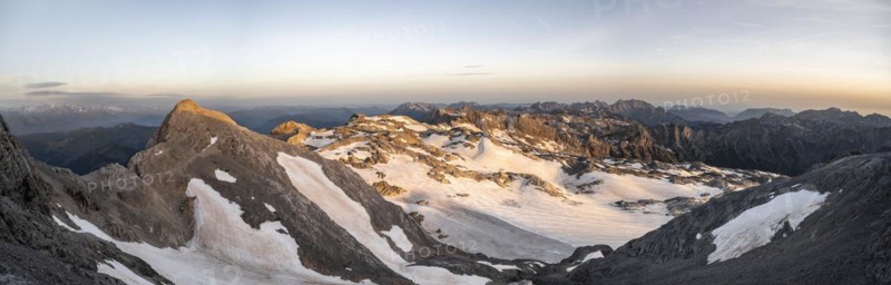 View of rocky plateau with snow and glacier at sunrise