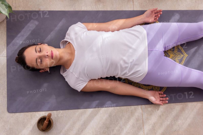 Young woman in a yoga studio relaxing in Shavasana pose