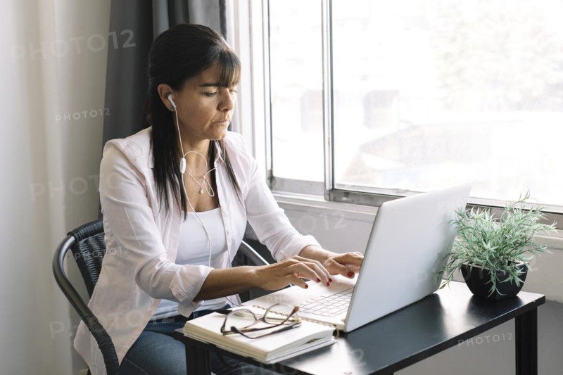 Businesswoman working on laptop computer sitting at home and managing her business through home office during Coronavirus or Covid-19 quarantine