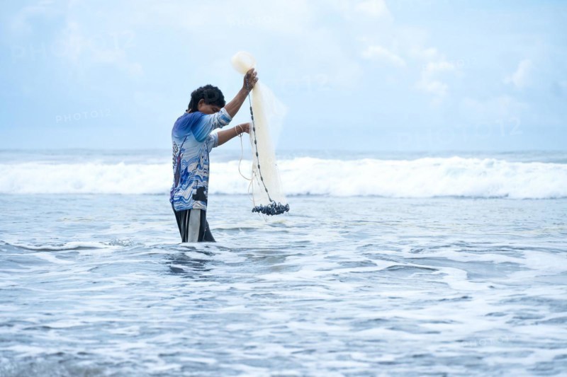 Side view of a fisherman in the sea preparing his net. Concept of sufficiency economy