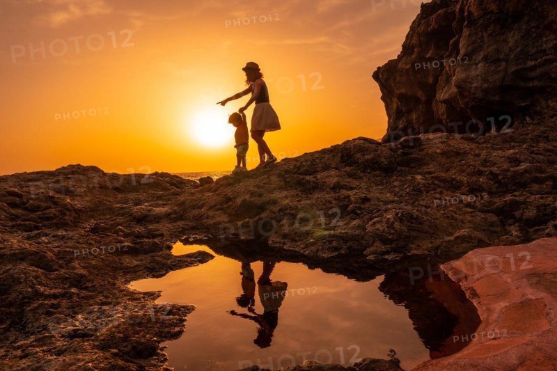Silhouette of mother and son walking in the sunset on the beach of Tacoron in El Hierro