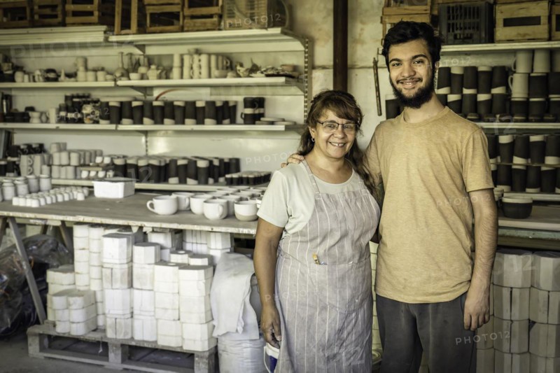 Wife and son smiling and looking at the camera in the ceramics studio. Family business
