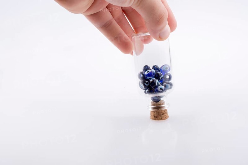 Little glass bottle with blue evil eye bead in hand