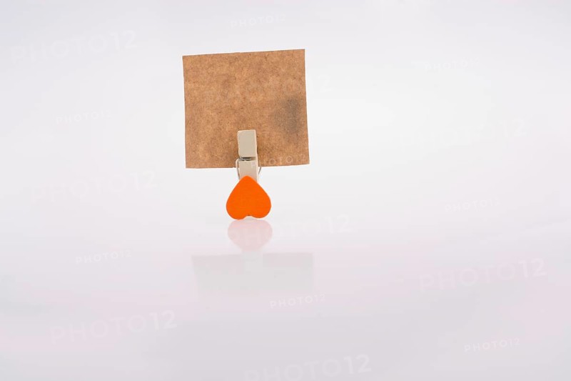 Heart shape clothespin attached to a note paper on a white background