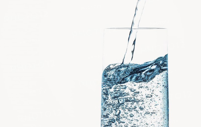 Water is poured bubbling into a clear glass