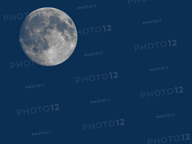 Full moon seen with telescope over blue with copy space