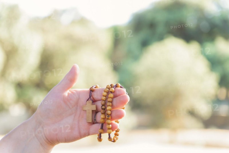 Woman's hands holding a Christian rosary with a cross