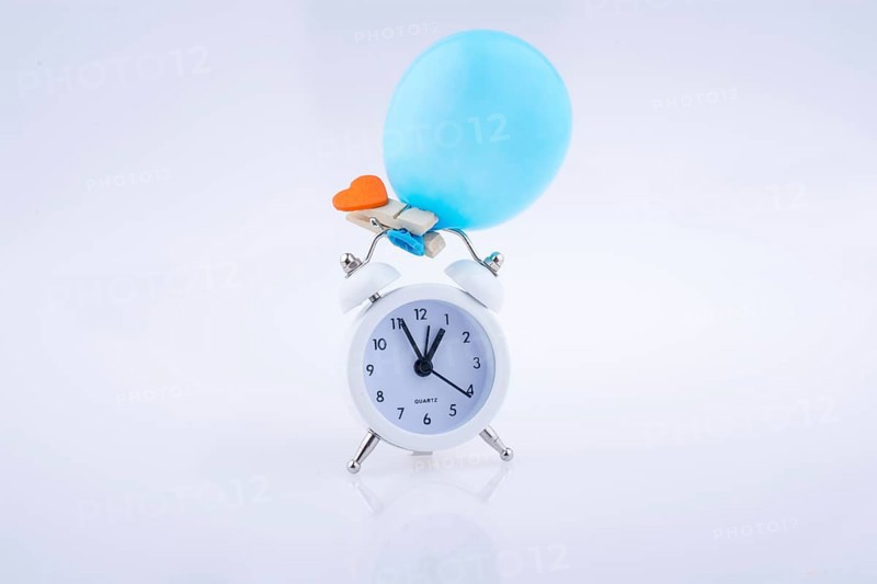 Alarm clock and a balloon with a heart on white background