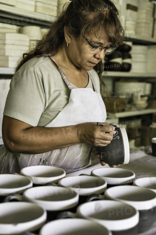 Craftswoman making the sgraffito on a piece of pottery