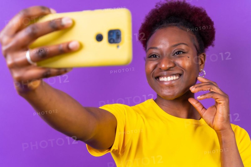 Young african american woman isolated on a purple background smiling and making a selfie