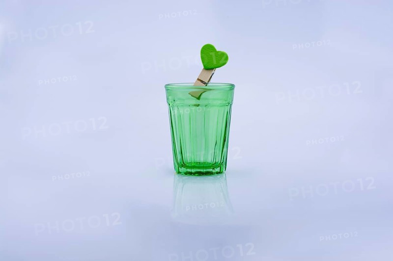 Drinking glass of gtreen color and a clothespin with a heart