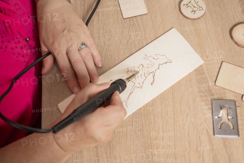 Close-up detail of a woman's hands drawing with an etching pencil