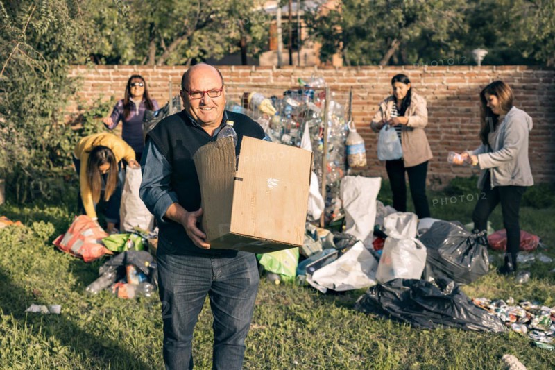 Group of happy volunteers separating recycling material. A man and group of women organizing material for recycling. Environmentalism