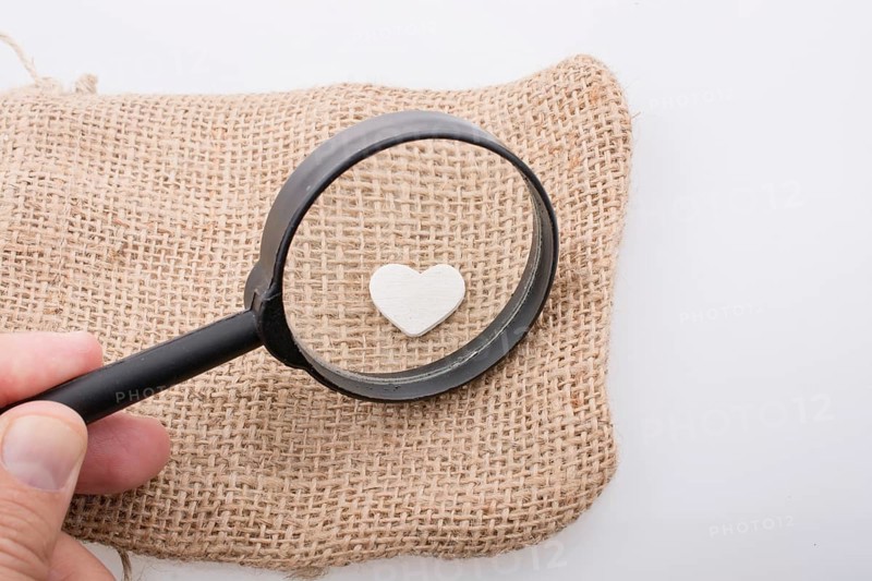 Heart shaped metal object behind magnifying glass