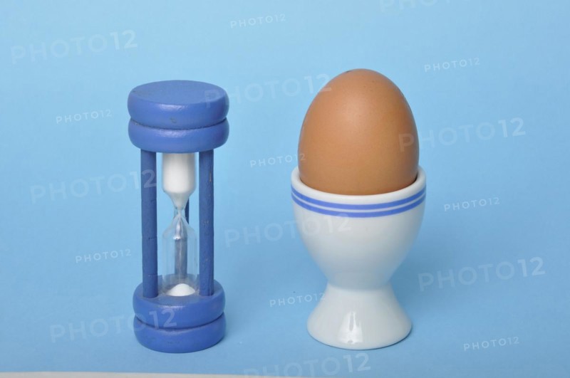 Boiled egg and hourglass on a blue background