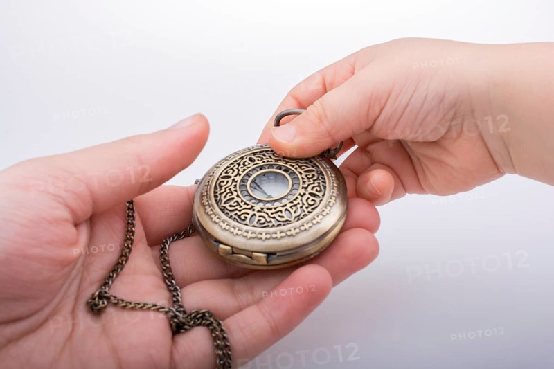 Retro style pocket watch in hand on white background