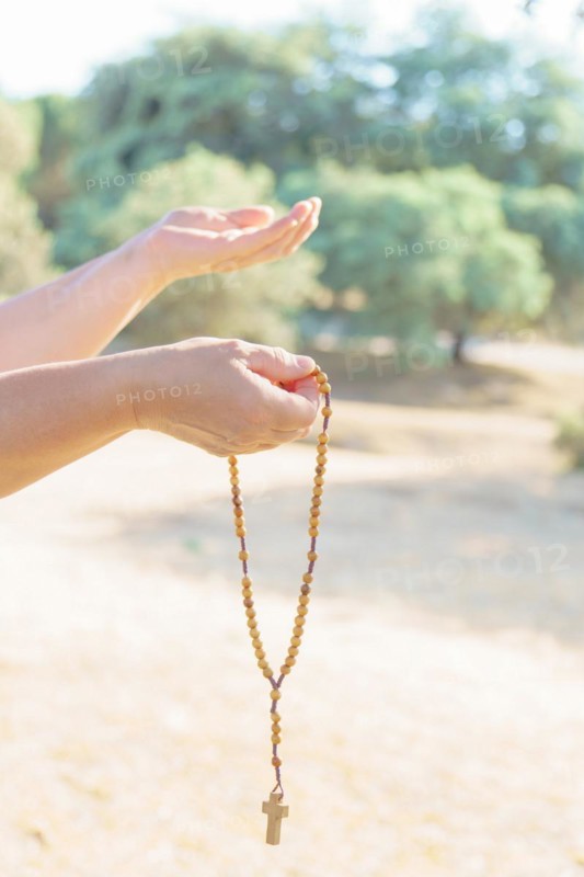Woman's hands holding a Christian rosary with a cross