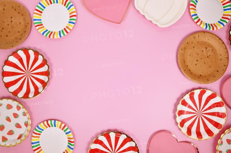 Colorful paper party plates forming border around pink background