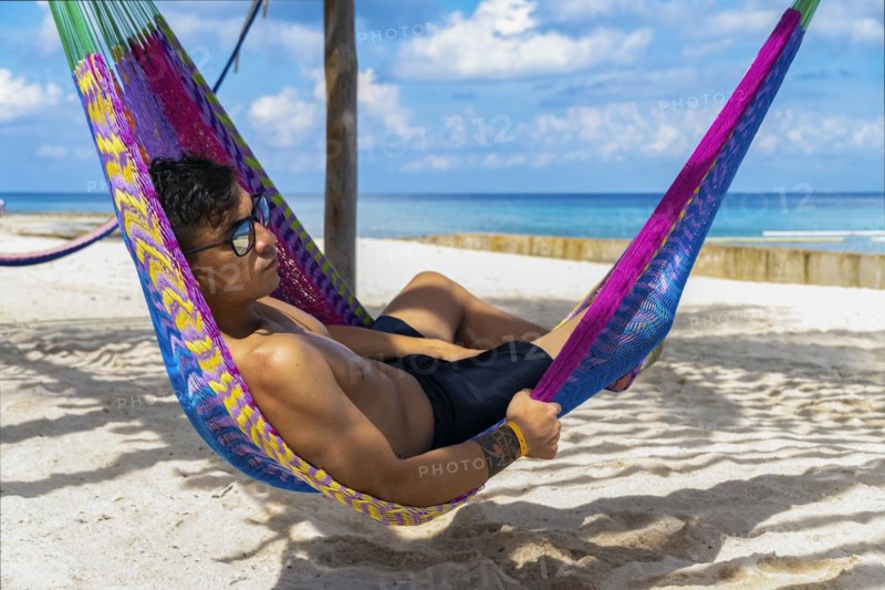 Handsome man relaxing in a hammock with Caribbean Sea in the background. Concept Vacation