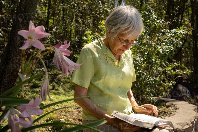 Serious mature woman reading in her garden