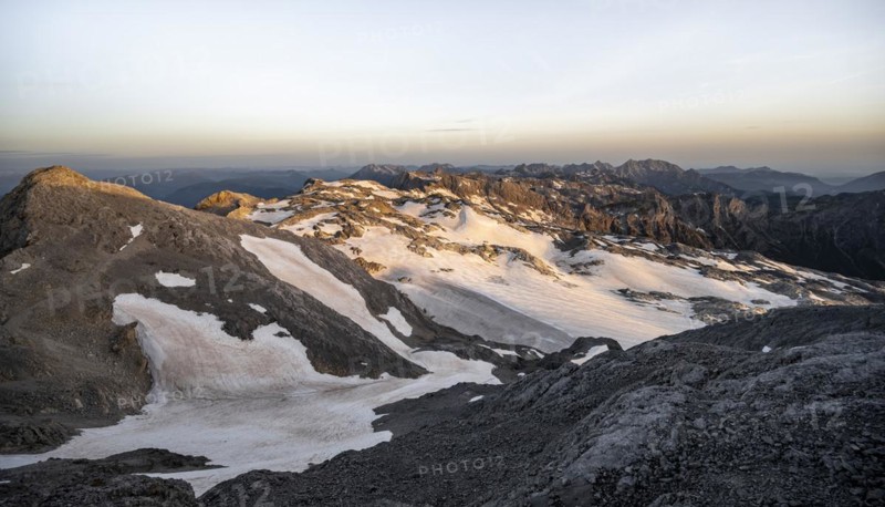 View of rocky plateau with snow and glacier at sunrise