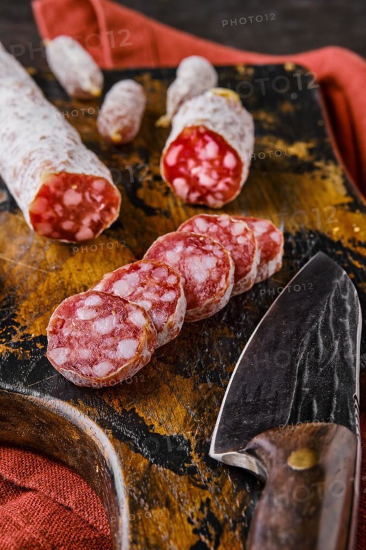 Fermented salami sausages on wooden cutting board cut on slices