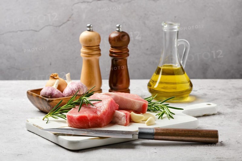 Raw fresh pork fillet cut on slices on kitchen table with spice