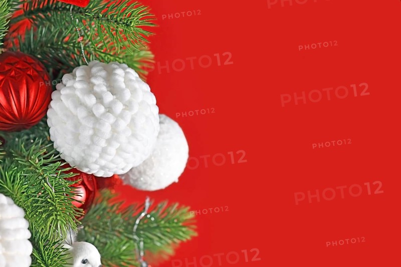 Fluffy white Christmas bauble on decorated tree with red background