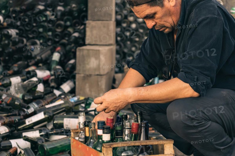Male volunteer working at a recycling centre. Glass bottles prepared for recycling. Concept of responsibility