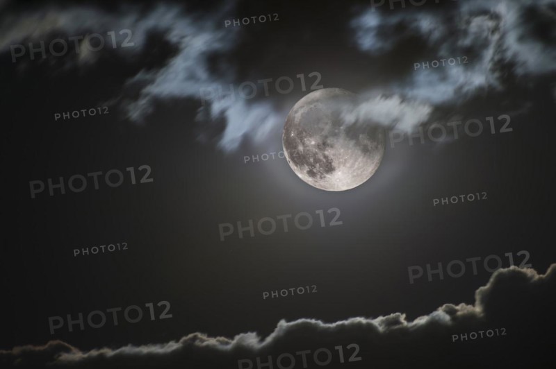 Rising full moon illuminates jagged cloud edge