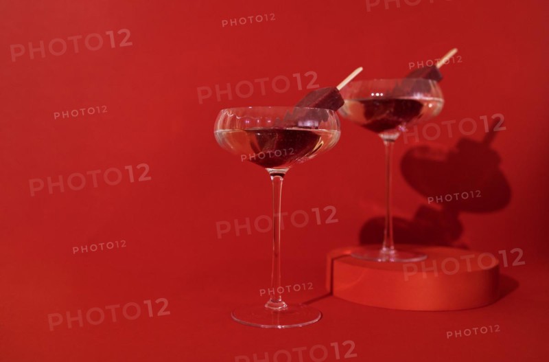 Two glasses of champagne and fruit ice cream on the podium. Stylish alcohol cocktail on red background. Delicious drinks concept. Copy space