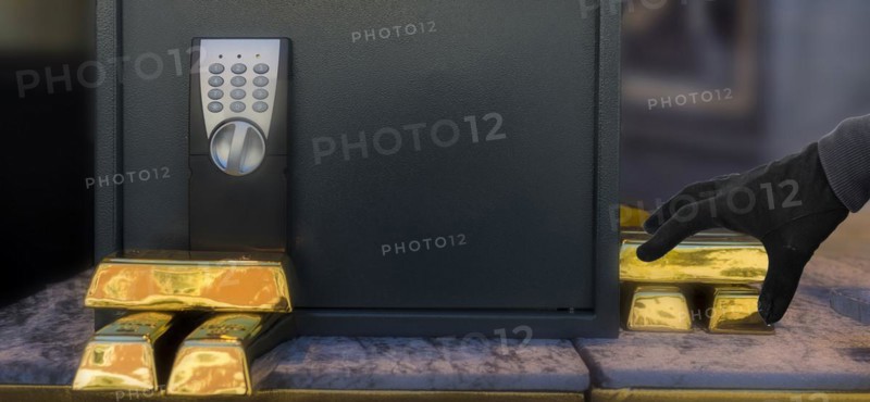 Gold bars in front of safe with thief