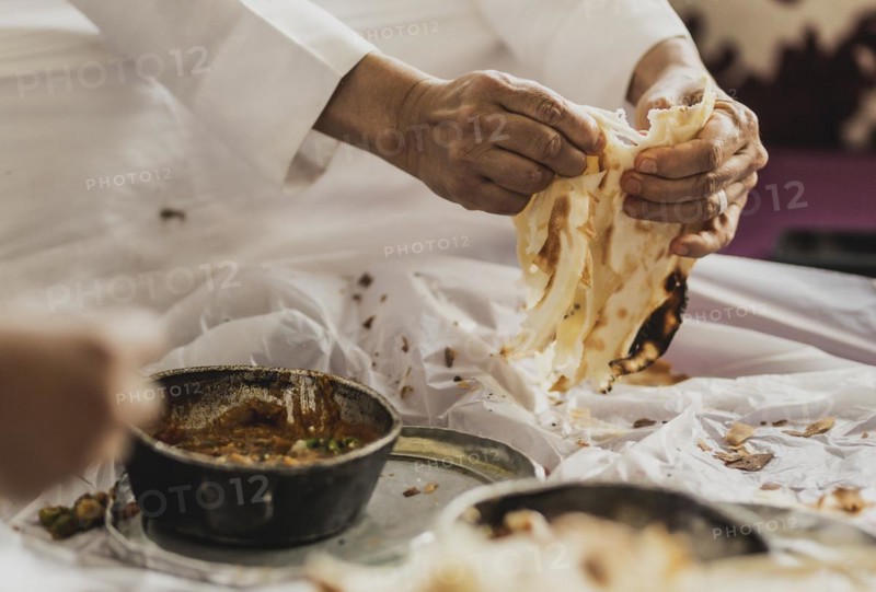 A man in traditional dress photographed with the Yemeni bread Malawach in Jeddah