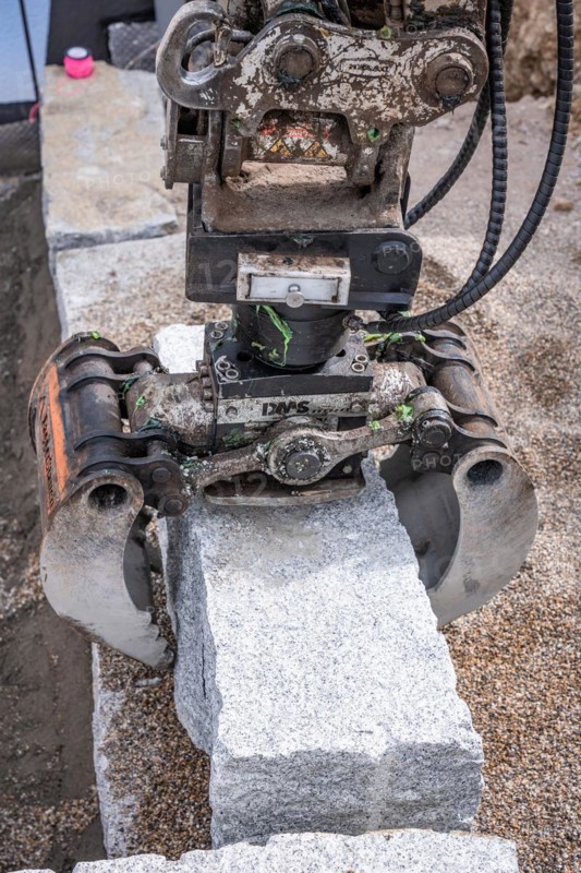 Excavator grab with stone on construction site