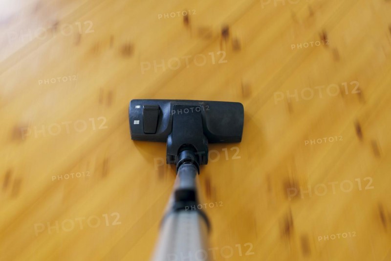 Symbolic photo on the subject of housework. A hoover sucks dust on a floorboard. Berlin