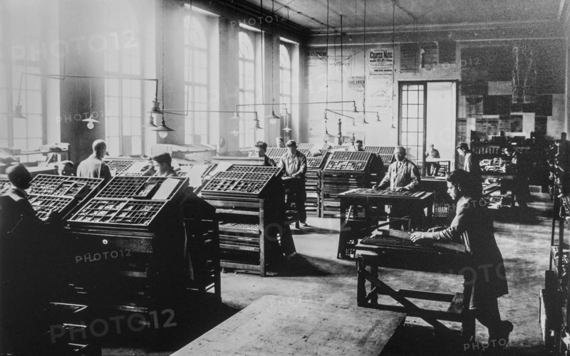 Early 20th century typesetters arranging types called typesetting for letterpress printing in print shop