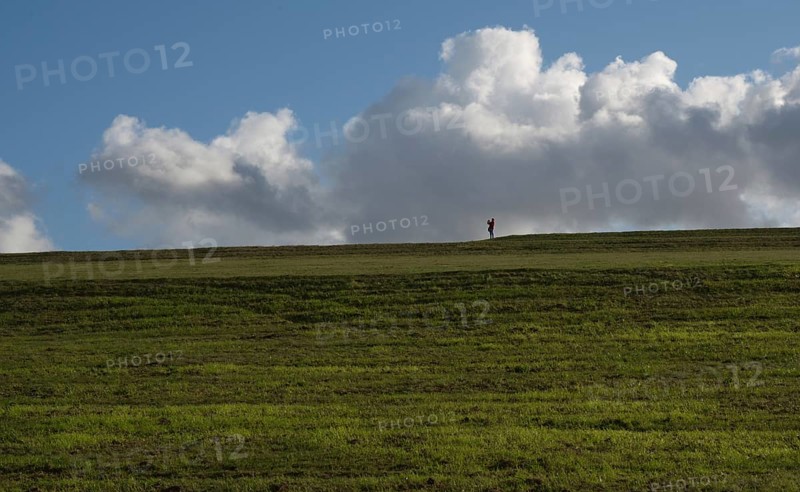 A woman takes a photo on the green former landfill site in Grossziethen