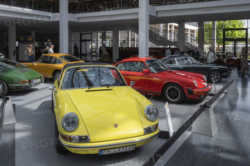 Porsche 911s lined up for presentation in an exhibition hall
